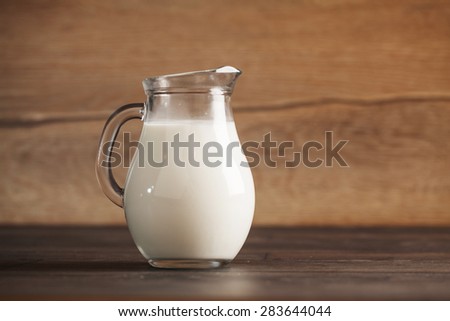 fresh milk in glass jug on wooden background. Selective focus.