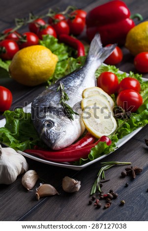 Fresh dorado fish on wooden cutting board with vegetable