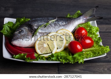 Fresh dorado fish on wooden cutting board with vegetable