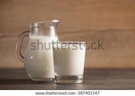 fresh milk in glass jug and glass on wooden background. Selective focus.