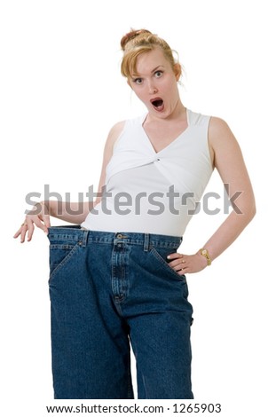 Woman demonstrating weight loss by wearing an old pair of jeans four sizes too big with a shocked expression on her face