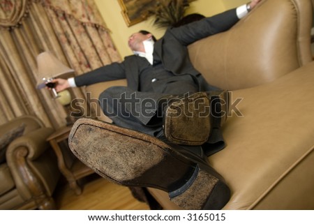 Man in a business suit sleeping on the sofa with a glass of red wine still in his hand