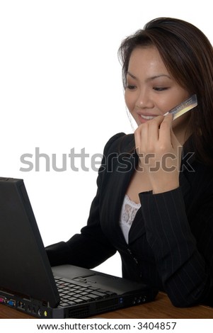 Attractive young asian woman in business attire sitting in front of a laptop computer holding onto a credit card