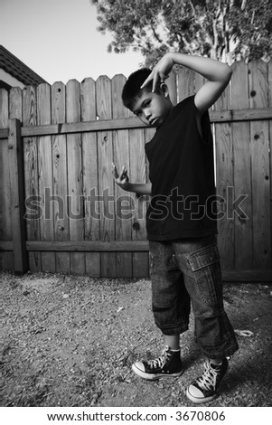 Young asian boy standing outside beside a tall wooden fence wearing jeans and black tshirt