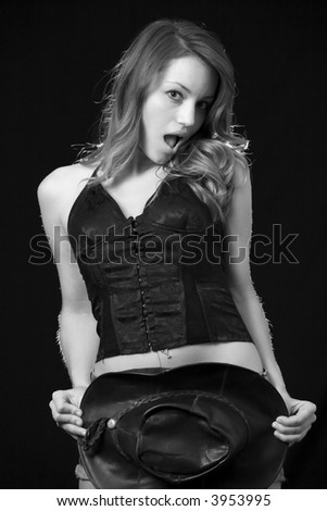beautiful brown hair woman wearing sexy black tank top using a cowboy hat to cover the bottom half of her body with a shocked expression on her face black background