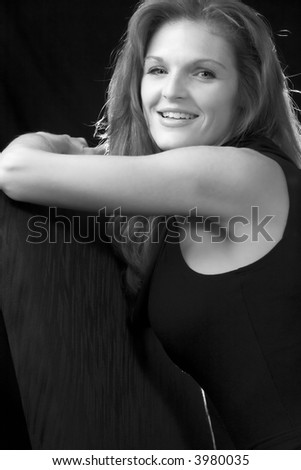 Beautiful red hair woman in black sitting on a black chair on black