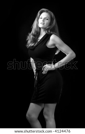Whole body of a beautiful red hair woman in black standing and posing on black