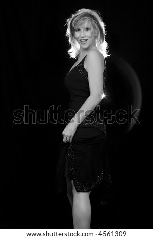 beautiful blond hair woman wearing black sexy dress posing on black background with rim light on hair