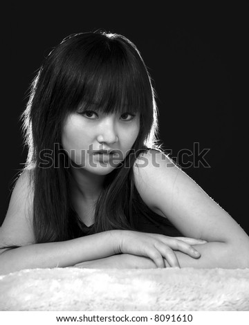 Portrait of a young Asian woman posing on black in black and white