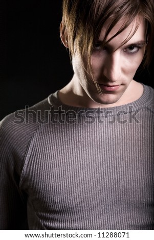 Close up head shot of a handsome young brunette man with serious expression and intense eyes