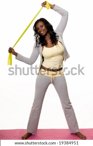 Attractive African American woman wearing workout attire standing on pink exercise mat stretching