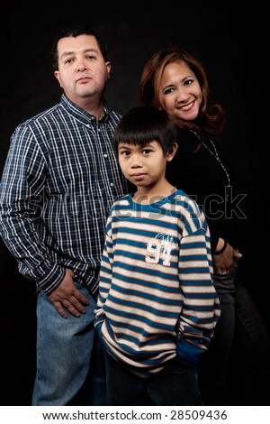 Portrait of a mixed race family with mother father and young son over black