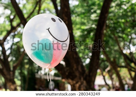 transparent  balloon with smile face on green bokeh background