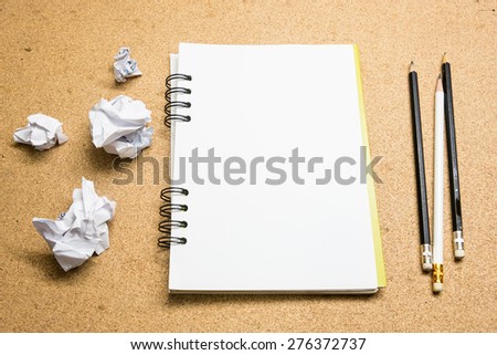 Notebook papers, pencil and crumpled paper ball  on wooden background