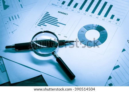 Data analyzing in forex market with magnifying glass, pen and calculator : the charts and summary info on paper. Charts of financial instruments for technical analysis.