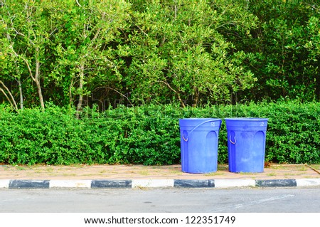 blue recycling bin in the park.