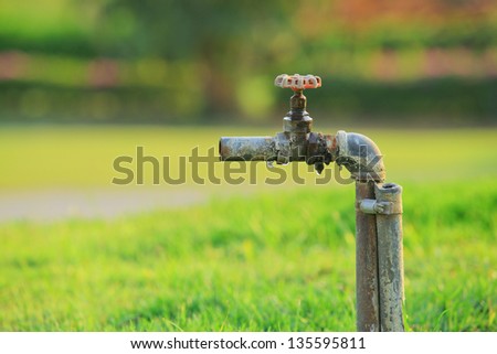 Old hydrant in the grass. The water shortage. The concept of water saving