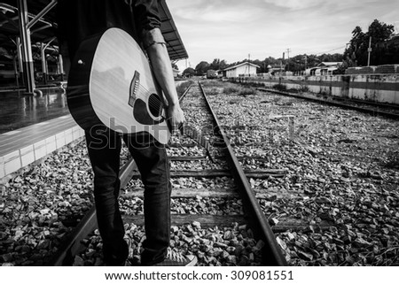 Guy with guitar on the railway road. Black and white photo