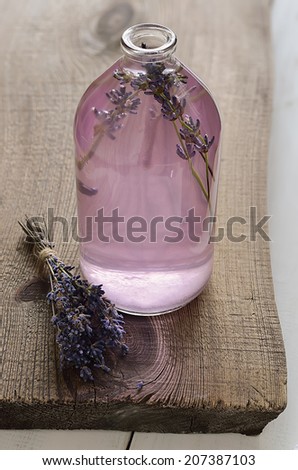 Homemade cosmetic infused lavender water in a glass bottle standing on a wooden board