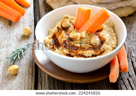 Freshly cooked chickpea hummus served with pita and carrots, decorated with olive oil and paprika powder
