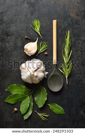 Grunge kitchen background with wooden spoon, garlic, bay leaves and rosemary