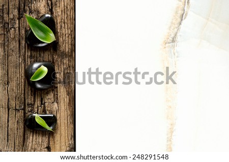 Spa background, zen stones decorated with green leaves on a weathered wood