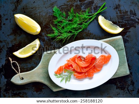 Smoked salmon served in an oval dish with lemon slices and dill, top view