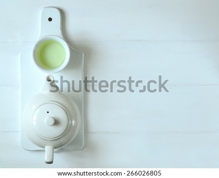 Green tea in tea pot and white cups, top view