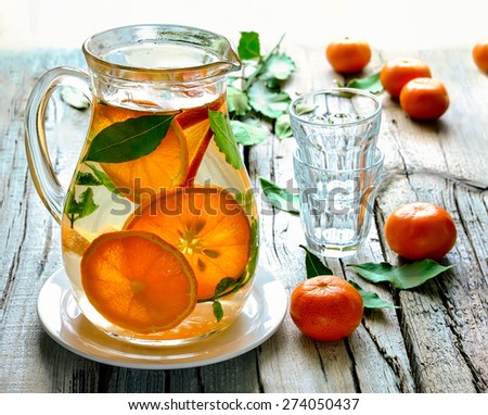 Homemade citrus infused water in a jug on a rustic background in a sunny day