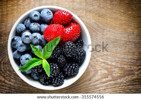 Various berries in a white bowl, top view