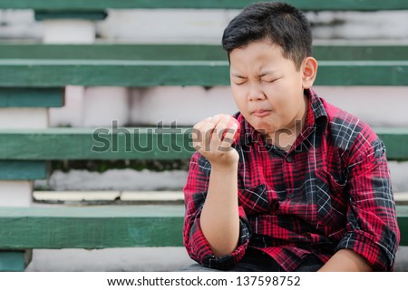 asian boy express pain while eating an apple