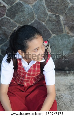 asian schoolgirl with ponytail sitting on concrete path