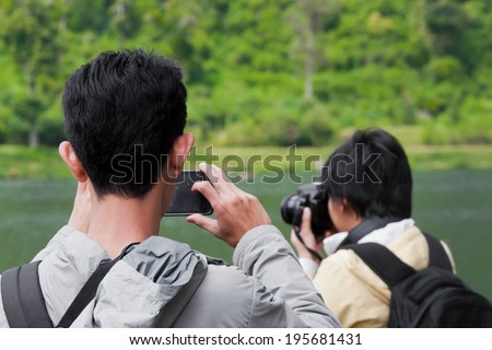 young man taking picture of a woman while taking picture of nature with digital camera