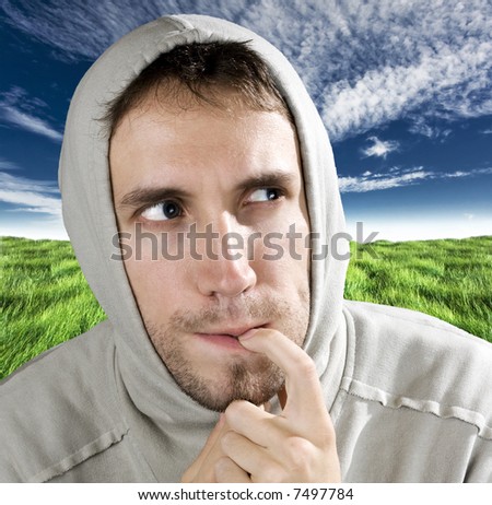Hooded man thinking with a finger in his mouth and looking away.