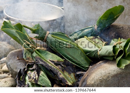 Cooking food wrapped in Banana Leaves on traditonal fire with charred leaves