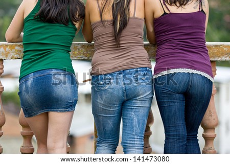 Three young ladies sight seeing with their backs to the camera, green in distance