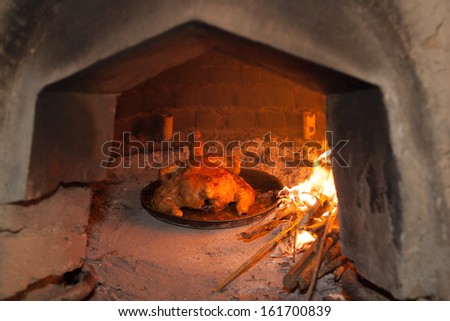 Traditional wood fired oven in the Andes region of Ecuador with flames and sticks with chicken cooking