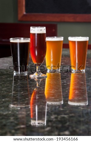 four different beers on granite bar top reflection