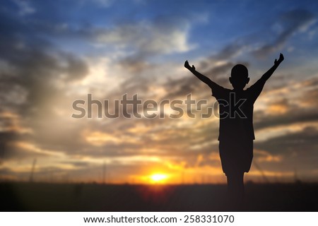 Silhouette of man with raised hands over blur nature concept for religion, worship, prayer and praise.
