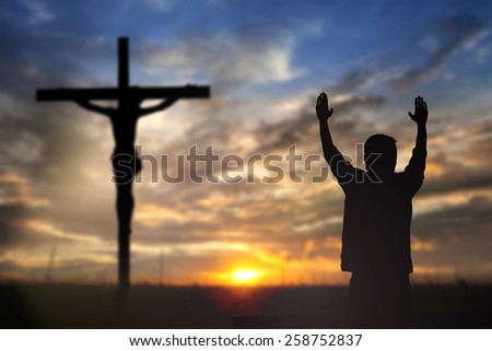 Silhouette of man with raised hands over blur cross concept for religion, worship, prayer and praise.