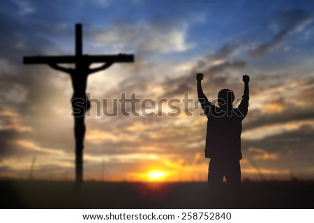 Silhouette of man with raised hands over blur cross concept for religion, worship, prayer and praise.