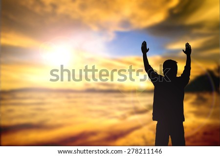 Silhouette of man with raised hands over blur sea concept for religion, worship, prayer and praise.