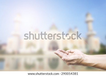 Human hands pray and mosque background.