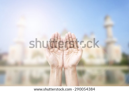 Human hands pray and mosque background.