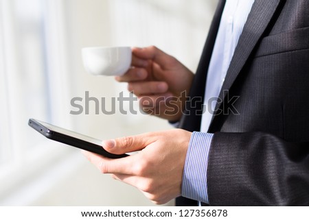 Businessman holding tablet pc and a cup of coffee