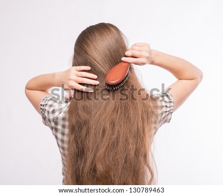 Young beautiful woman combing her luxuriant hair