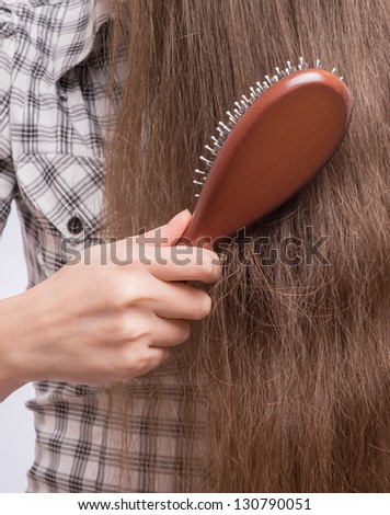 Young beautiful woman combing her luxuriant hair