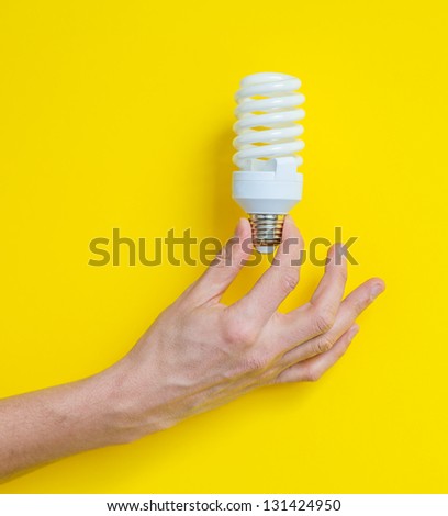 Light bulb in hand on a yellow background
