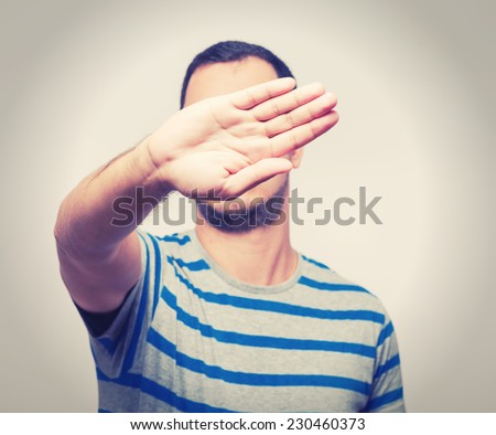 Young Caucasian man hiding his face with hand