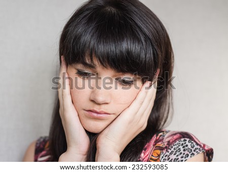 Woman with headache holding head with hands and have grimace on his face.
